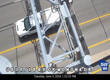 White vehicle, possibly police, stopped on roadway near traffic signal structure.