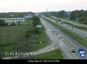 Emergency responders are visible on the highway with flashing lights.