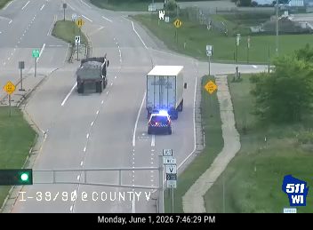 Police car with flashing lights behind a truck on the highway.