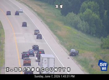 Police car stopped on the shoulder of the highway with its lights on.