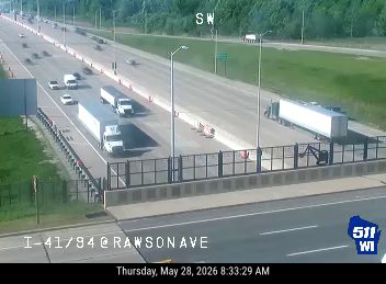 Construction vehicle and personnel on the shoulder of the highway.