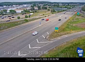 White emergency vehicle on the shoulder of the highway with traffic moving past.