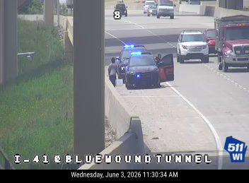 Police car with lights on, officers present on the shoulder.