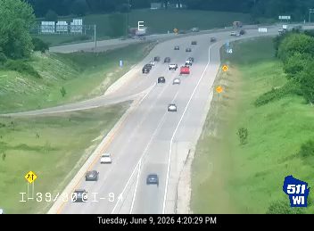 Emergency cones and a vehicle are present on the roadside, indicating a possible incident.