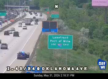 Police car with open door and flashing lights on the shoulder.