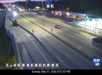 Construction vehicle and cones on the left shoulder of the highway.