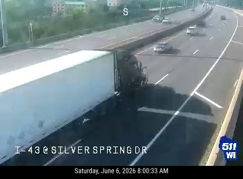 A semi-truck appears to have crashed and is blocking multiple lanes of traffic.
