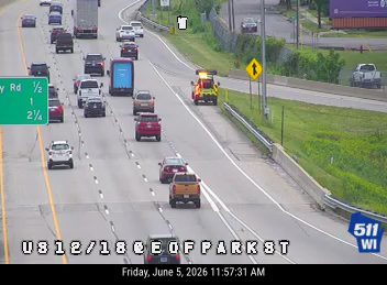 Emergency vehicle on the right shoulder of the highway with lights on.