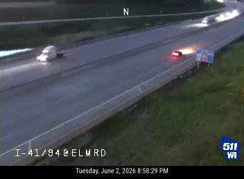 Vehicle fire on the right shoulder of the highway with flames visible.