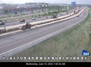 Construction vehicles and workers are present on the roadway, indicating ongoing work.