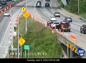 Emergency vehicle and crew on the side of the road with traffic control cones.