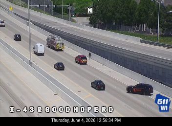 Fire truck and police vehicle on the highway shoulder with personnel present.