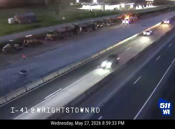Construction vehicles and emergency lights suggest a roadside incident or work zone.