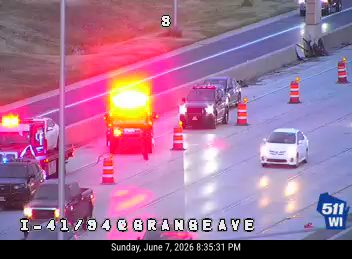 Emergency responders with flashing lights and cones on the highway.