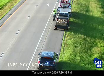 Road crew with vehicles and personnel on the shoulder of the highway.