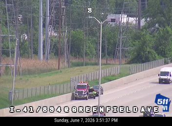 Emergency responders and tow truck assisting a vehicle on the side of the road.