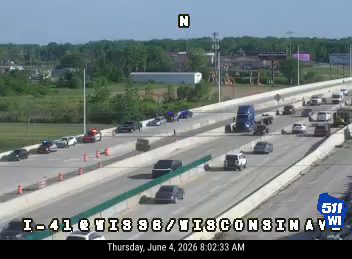 Emergency responders and vehicles on the highway shoulder, traffic slowed.