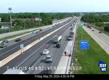 Police officer and vehicle on the shoulder of the highway.