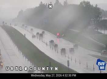 Emergency vehicle with lights on, responding to an incident on a wet highway.
