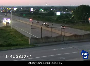 Two emergency vehicles with lights on are stopped on the highway shoulder.