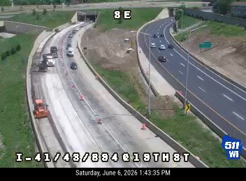Construction equipment and cones indicate ongoing road work with potential traffic disruption.