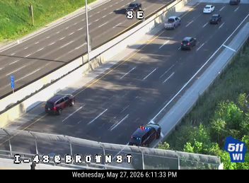 Police cars are stopped on the shoulder, possibly responding to an incident.