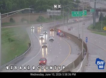 Police car and other vehicles stopped on the highway shoulder during rain.