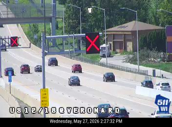 Traffic camera shows a police car with lights on blocking a lane.