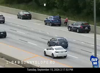 Person standing on the right shoulder near a vehicle
