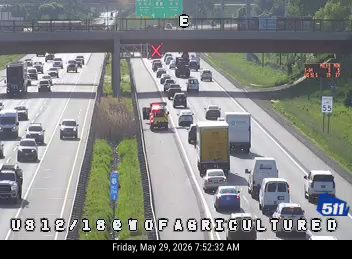 Emergency vehicle with lights on, traffic stopped behind it on highway.