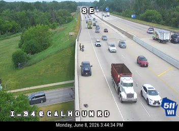 Police car and two individuals on the shoulder of I-94 near Calhoun Road.