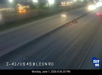 Emergency responders with cones and vehicles on the highway shoulder.