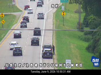 Police officer assisting a vehicle on the shoulder of the road.