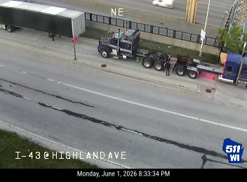 Two trucks stopped on the highway, people appear to be working on them.