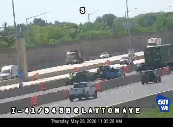 Emergency responders and cones on highway, traffic slowed.