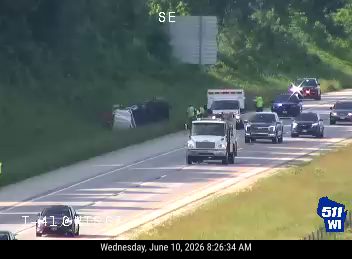 Vehicle overturned on the side of the road with emergency responders present.