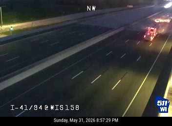 Fire truck on the highway shoulder with lights on.