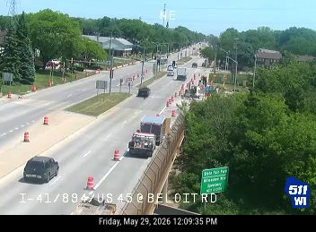 Construction vehicles and cones indicate a possible incident or road work on the highway.