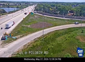 Emergency vehicles and equipment are present on the shoulder of the highway.