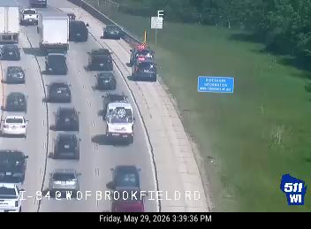 Emergency responders and vehicles are present on the right shoulder of the highway.