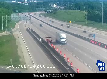 A white truck is stopped on the shoulder with cones and equipment nearby.