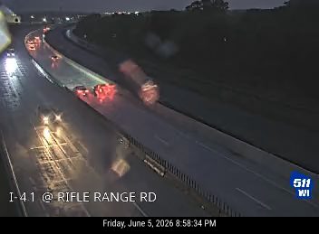 Multiple vehicles stopped on highway, red lights indicating brake lights on. Possible crash.
