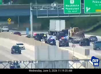 Police and emergency vehicles on the highway shoulder with flashing lights.