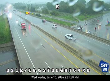 Vehicle appears to have crashed and is emitting smoke on a wet highway.