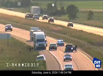 Two vehicles appear to be involved in a crash on the right shoulder of the highway.