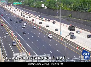 Emergency vehicle and cones on the right shoulder of the highway.