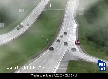 Emergency vehicle with lights on at roadside, traffic slowing.