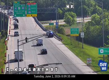 Emergency vehicle with lights on, stopped on the highway shoulder.
