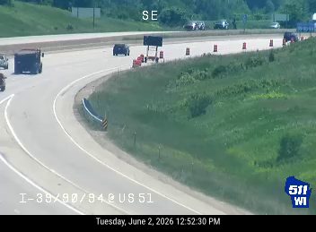Emergency responders and equipment on the highway shoulder with traffic cones.