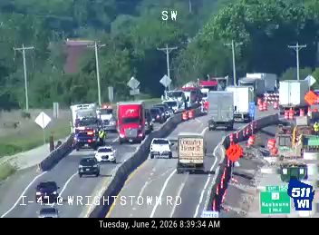 Construction vehicles and cones indicate ongoing road work with potential traffic disruption.